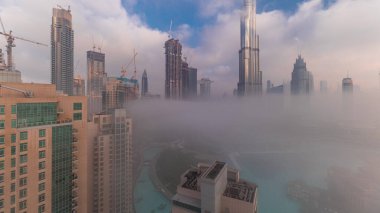 Sabahın erken saatlerinde sis sırasında Dubai şehrinin hava görüntüsü. Gökdelenler ve gökdelenlerle dolu fütüristik şehir siluetinde gün doğumu. Güneş, ışık ışınlarıyla cam yüzeyden yansıyor.