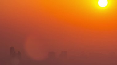 Sunrise close up view over Dubai skyline in the morning, aerial top view from Dubai marina . Big sun on orange sky rise over fog around skyscrapers. United Arab Emirates