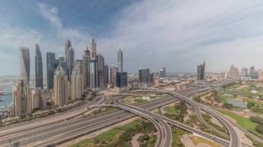 Dubai Marina karayolu kavşağındaki panorama spagetti kavşağı bütün gün sürdü. Arka planda hızla hareket eden gölgeli en uzun gökdelenler. JLT bölgesinden hava görüntüsü. Bulutlu gökyüzü