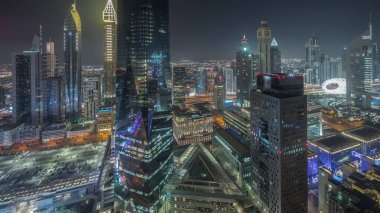 Panorama showing futuristic skyscrapers in financial district business center in Dubai on Sheikh Zayed road night . Aerial view from above with illuminated towers