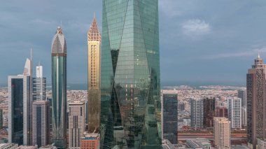 Financial center of Dubai city with illuminated luxury skyscrapers night to day transition , Dubai, United Arab Emirates. Aerial view with light in windows and office towers