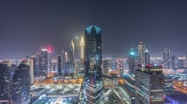 Panorama of futuristic skyscrapers in financial district business center in Dubai on Sheikh Zayed road during all night . Aerial view from above with illuminated towers and moon