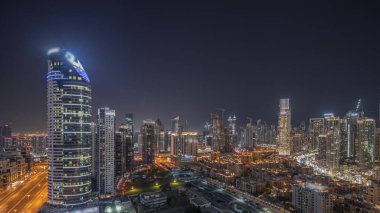 Panorama showing Dubai's business bay and downtown towers with old town aerial night . Rooftop view of some skyscrapers and new towers under construction