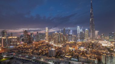 Dubai Downtown panorama day to night transition  with tallest skyscraper and other towers view from the top after sunset in Dubai, United Arab Emirates. Lights turning on.