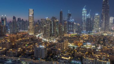 Close up view to Dubai's business bay towers aerial day to night transition . Rooftop view of some skyscrapers and new towers under construction after sunset
