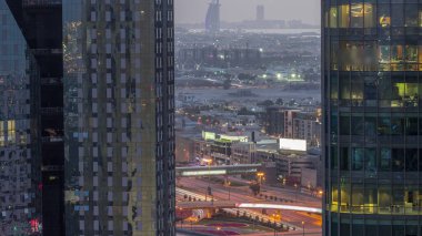 Şehir merkezinden Dubai 'ye uzanan ufuktaki villalar ve ünlü otel kavşağında büyük bir hava gününden geceye geçiş var. Parlak pencereli gökdelenler tarafından çerçevelenmiş
