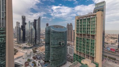 Panorama showing Dubai international financial center skyscrapers with promenade on a gate avenue aerial . Many office towers and traffic on a highway. Cloudy sky