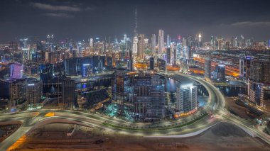 Dubai 'nin panoramik silueti, iş hangarı inşaatı ve şehir merkezi gece. Birçok modern gökdelenin ve Al Khail yolundaki yoğun trafiğin havadan görüntüsü. Birleşik Arap Emirlikleri.