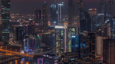 Skyline with modern architecture of Dubai business bay towers day to night transition . Aerial view with canal and construction site after sunset with colorful sky