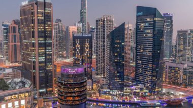 Dubai Marina Skyline 'da JLT semti gökdelenleri var. Hava gününden geceye geçiş gününde. Güneş battıktan sonra cam yüzeyi ve rıhtımı olan kuleler.
