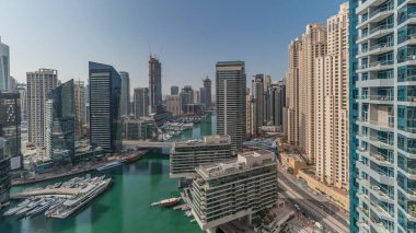 Panorama showing aerial view to Dubai marina skyscrapers around canal with floating boats and jlt with jbr districts . White boats are parked in yacht club