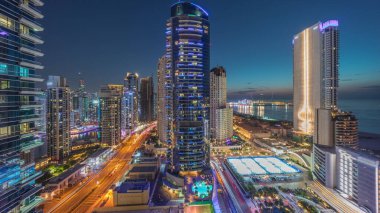 Panoramic view of the Dubai Marina and JBR area and the famous Ferris Wheel aerial day to night transition . Golden sand beaches in the Persian Gulf after sunset