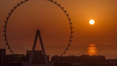 Sunset over Bluewaters island with modern architecture and ferris wheel aerial  close up view. New leisure and residential area near Dubai marina and JBR. Orange sky
