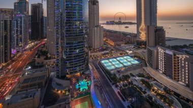 Dubai Marina ve JBR bölgesinin panoramik manzarası ve Ferris Wheel hava gününden geceye geçiş. Basra Körfezi 'nde gün batımlı altın kumlu plajlar