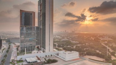 Sunrise in Dubai International Financial district transition . Aerial view of business office towers at morning. Skyscrapers with hotels near downtown