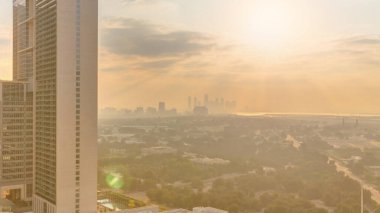 Sunrise over garden in Zabeel district with skyscrapers on a background aerial  in Dubai, UAE. Orange clouds on the sky with rays of sun light