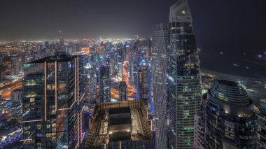 Panorama showing JBR district and Dubai Marina with JLT. Traffic on highway between skyscrapers aerial night . Illuminated modern towers and construction site