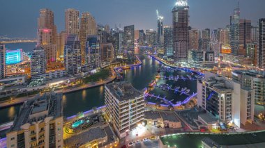 Dubai Marina 'da limana park etmiş birkaç tekne ve yatla ve hava kanallarının etrafındaki gökdelenlerle. JBR bölgesinin kuleleri ve vinçli şantiye