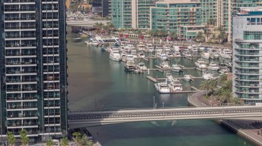 Birçok yat ve tekne bütün gün boyunca liman havasında park halindedir ve gölgeler hızla hareket eder. Dubai Marina rıhtımı yürüyüş alanı. Modern tekne derede yüzüyor..