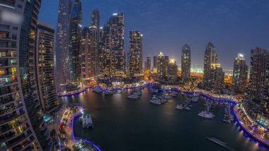 Dubai marina tallest skyscrapers panorama and yachts in harbor aerial night after sunset. View at apartment buildings, hotels and office blocks, modern residential development of UAE