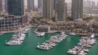 Şatafatlı yat körfezi Dubai marinasında sabah güneş doğduktan sonra. Rıhtım boyunca modern gökdelenler ve limanda yüzen tekneler.