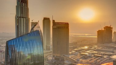Aerial sunrise panorama of Downtown Dubai with shopping mall and traffic on a street morning  from above, UAE. Modern skyscrapers and hotels. Orange sky