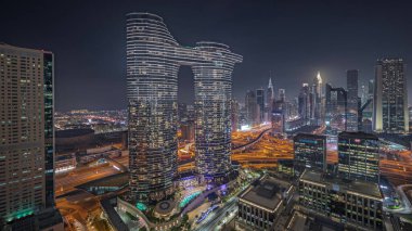 Panorama showing futuristic Dubai Downtown and finansial district skyline aerial night . Many illuminated towers and skyscrapers with traffic on streets