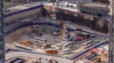 Vinçler ve buldozerler yeni gökdelen anteninin şantiyesinde çalışıyorlar. İşçilerle dolu otobüsler. Arazi temizliği, not verme, havuz kazma, siper kazma ve temel kazma. Sürüngen çekici