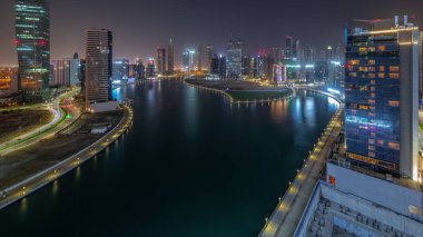 Dubai İş Koyu 'ndaki deniz manzarası ve gökdelenler gece boyunca su kanalı antenli. Aydınlatılmış kuleleri ve ışıkları olan modern gökyüzü. Uluslararası bir iş merkezi.