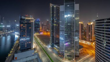 Dubai Business Bay 'de ve şehir merkezinde bütün gece boyunca su kanalları antenli gökdelenler. Aydınlatılmış kuleleri ve rıhtımı olan modern gökyüzü. Işıklar kapanıyor.