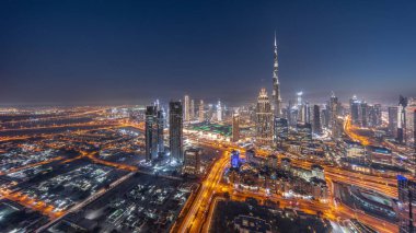 Aerial view of tallest towers in Dubai Downtown skyline and creek area day to night transition . Financial district and business area in smart urban city. Skyscraper and high-rise buildings