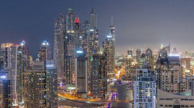 Dubai Marina hava sahasının en yüksek bloğundaki çeşitli gökdelenlerin görüntüsü suni kanalla gündüz gece geçişi. Gün batımından sonra birçok kule ve yat