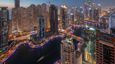 Dubai Marina ve JBR bölgesindeki çeşitli gökdelenlerin görüntüsü suni kanalla gündüz-gece geçişi. Gün batımından sonra birçok kule ve yat