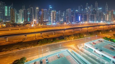 Dubai marinası tüm gece boyunca gökdelenlerin en yüksek bloğu ve ışıkları kapalı. JLT bölgesinden apartman binalarına, otellere ve otoyola yakın ofis kulelerine hava panoramik görüntüsü.