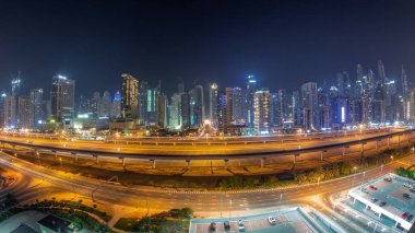 Tüm gece boyunca Dubai Marina gökdelenleri ve Şeyh Zayed yolu metro antenli panorama. Modern kulelerin yakınındaki bir otoyolda trafik var, Birleşik Arap Emirlikleri