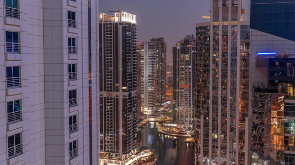 Tall residential buildings at JLT district aerial day to night transition , part of the Dubai multi commodities centre mixed-use district. Illuminated towers with glowing windows