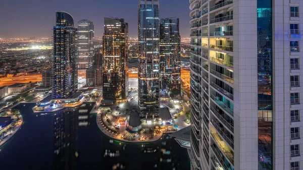 Tall residential buildings at JLT district aerial day to night transition , part of the Dubai multi commodities centre mixed-use district. Many balconies on towers