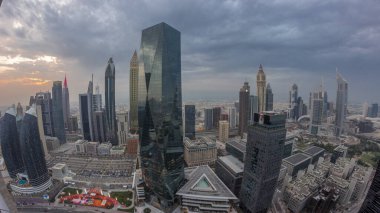 Panorama of futuristic skyscrapers with sunset in financial district business center in Dubai on Sheikh Zayed road . Aerial view from above with orange cloudy sky