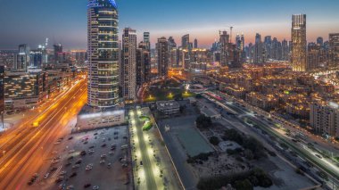 Panoramic view to Dubai's business bay towers aerial day to night transition . Rooftop view of some skyscrapers and new buildings under construction after sunset