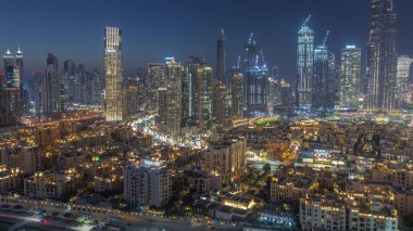 Close up view to Dubai's business bay towers aerial day to night transition . Rooftop view of some skyscrapers and new towers under construction after sunset