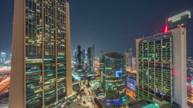 Tüm gece boyunca Dubai Uluslararası Finans Merkezi gökdelenleri. Aydınlatılmış kuleler yukarıdan görünüyor ve ışıklar sönüyor