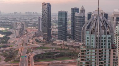 Huge highway crossroad junction between JLT district and Dubai Marina intersected by Sheikh Zayed Road aerial night. Golf course near illuminated towers and skyscrapers with busy traffic