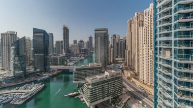 Panorama showing aerial view to Dubai marina skyscrapers around canal with floating boats and jlt with jbr districts . White boats are parked in yacht club