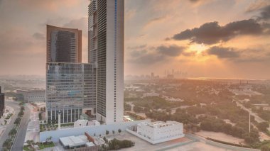 Sunrise in Dubai International Financial district transition . Aerial view of business office towers at morning. Skyscrapers with hotels near downtown