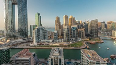 Panorama showing Dubai Marina skyscrapers and JBR district with luxury buildings and resorts aerial . Waterfront with palms and boats floating in canal