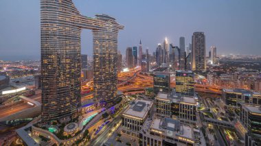 Fütürist Dubai Şehir Merkezi ve finans bölgesi gökyüzü gününden geceye geçiş. Birçok aydınlık kule ve gökdelenler caddelerde trafik var.