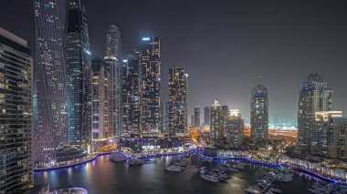 Panorama showing Dubai marina tallest skyscrapers and yachts in harbor aerial night . View at apartment buildings, hotels and office blocks, modern residential development of UAE