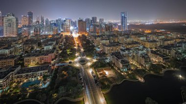 Panorama showing skyscrapers in Barsha Heights district and low rise buildings in Greens district aerial night . Dubai skyline with palms and trees