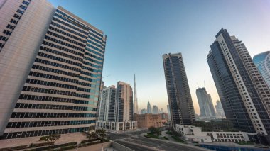 Aerial panoramic looking up view to Dubai downtown and difc skyscrapers with busy traffic on intersection in Business bay district night to day transition .