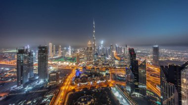 Aerial panorama of tallest towers in Dubai Downtown skyline and highway day to night transition . Financial district and business area in smart urban city. Skyscraper and high-rise buildings